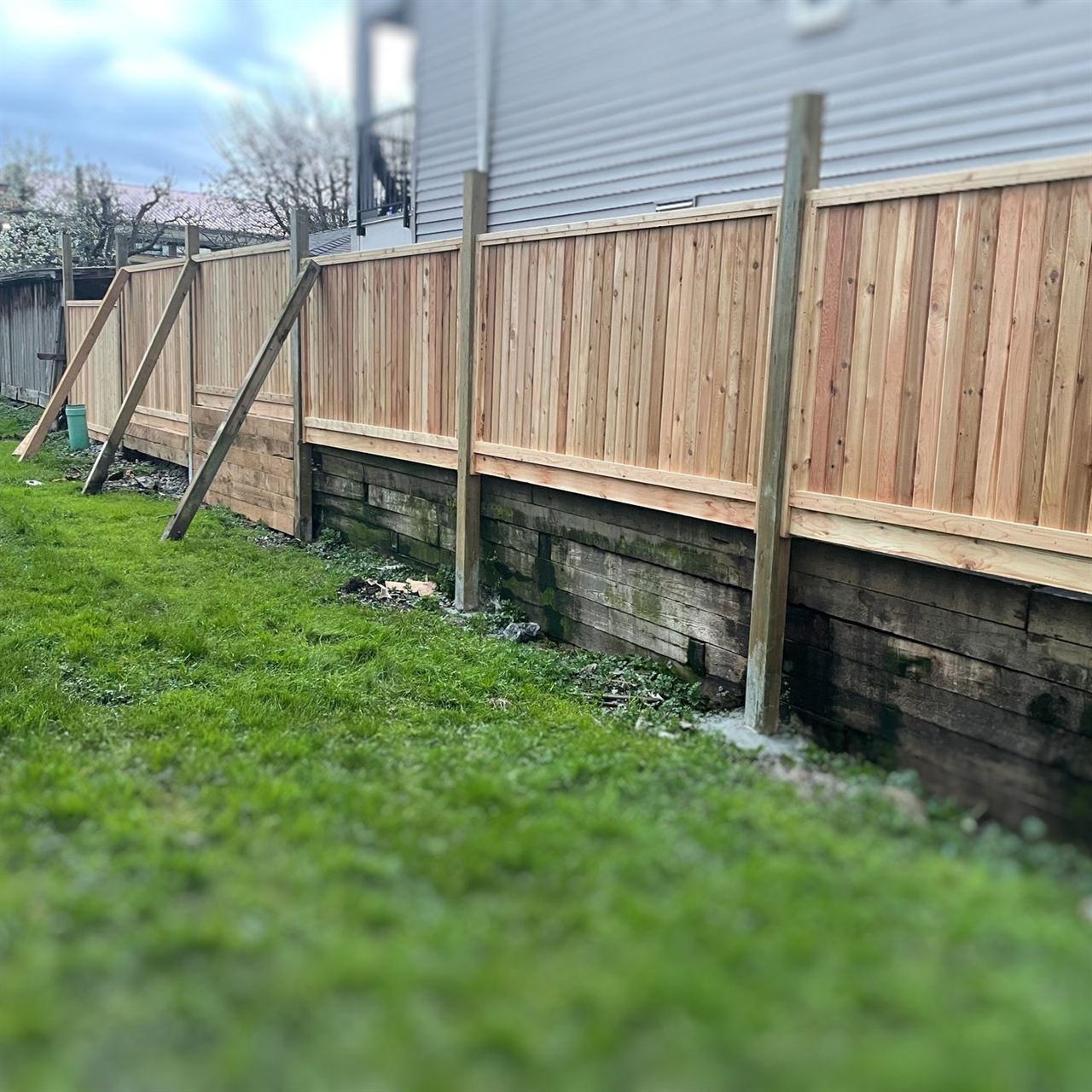 New cedar fence built atop an existing timber retaining wall
