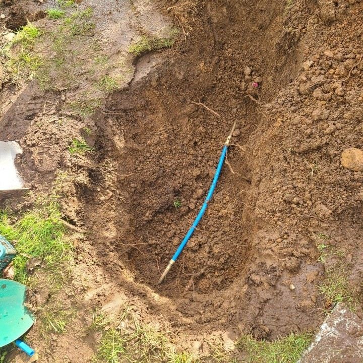 Blue poly water service line exposed in an excavated repair hole