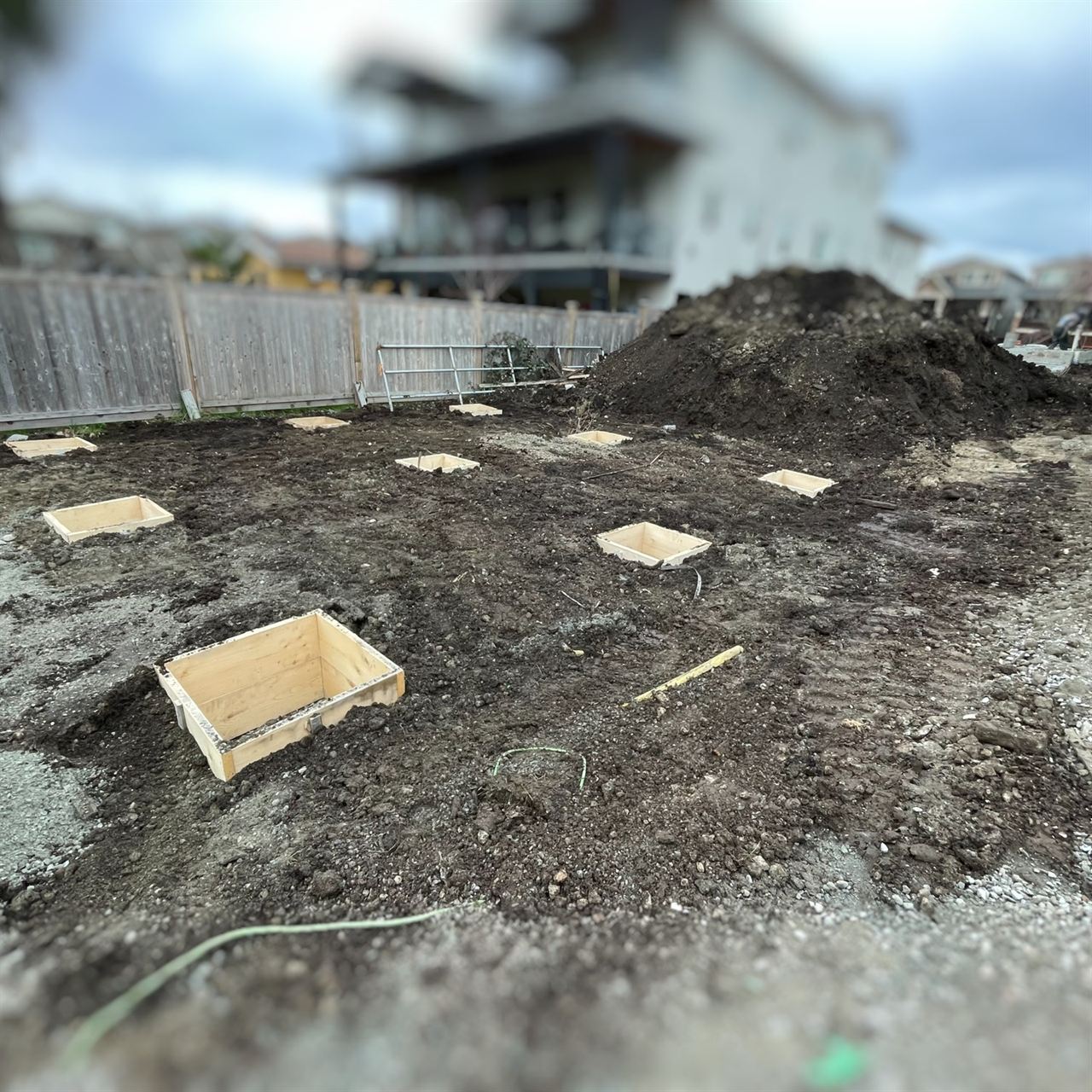 Footing form boxes laid out across an excavated lot