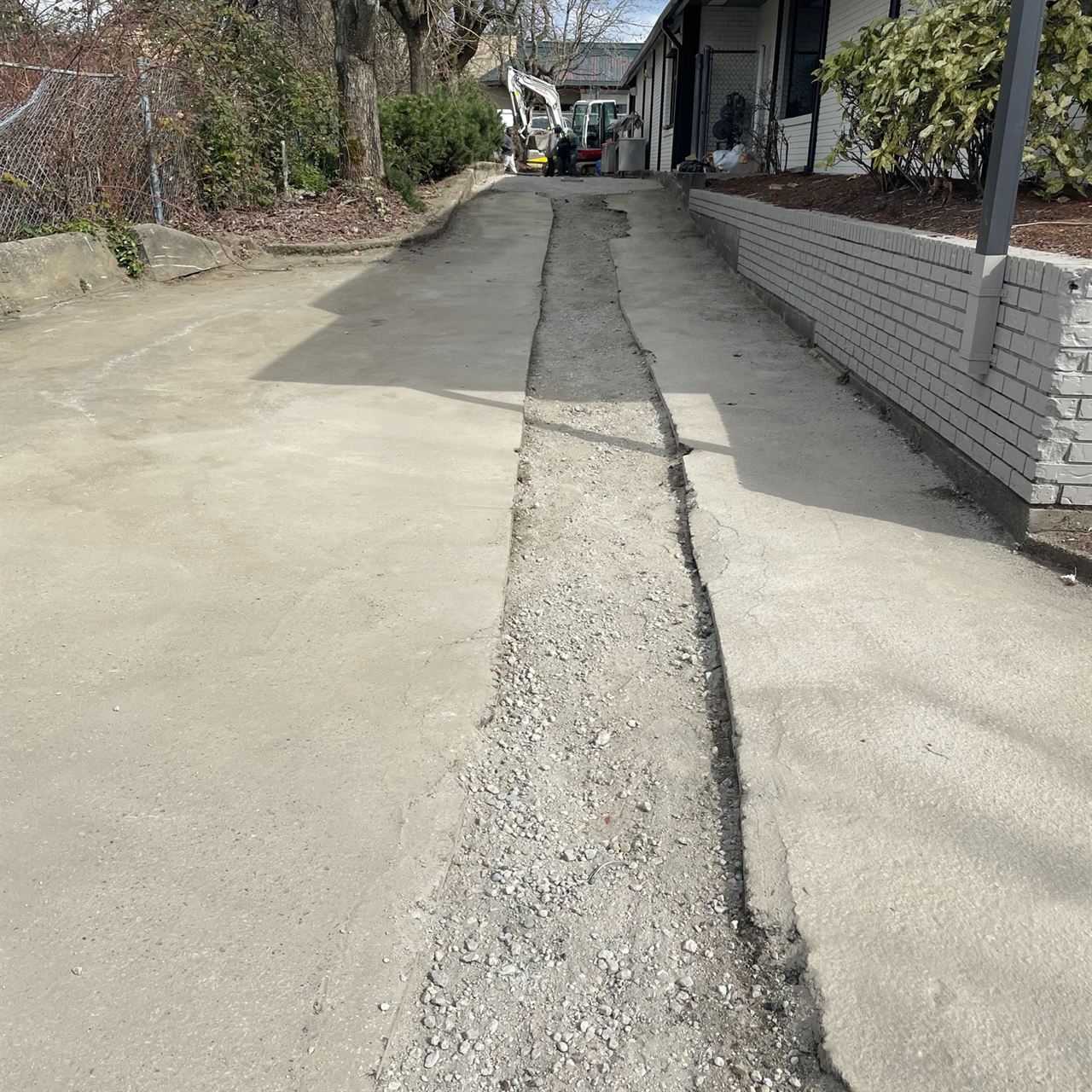 Asphalt paving prep — driveway surface opened with central trench for utility lines