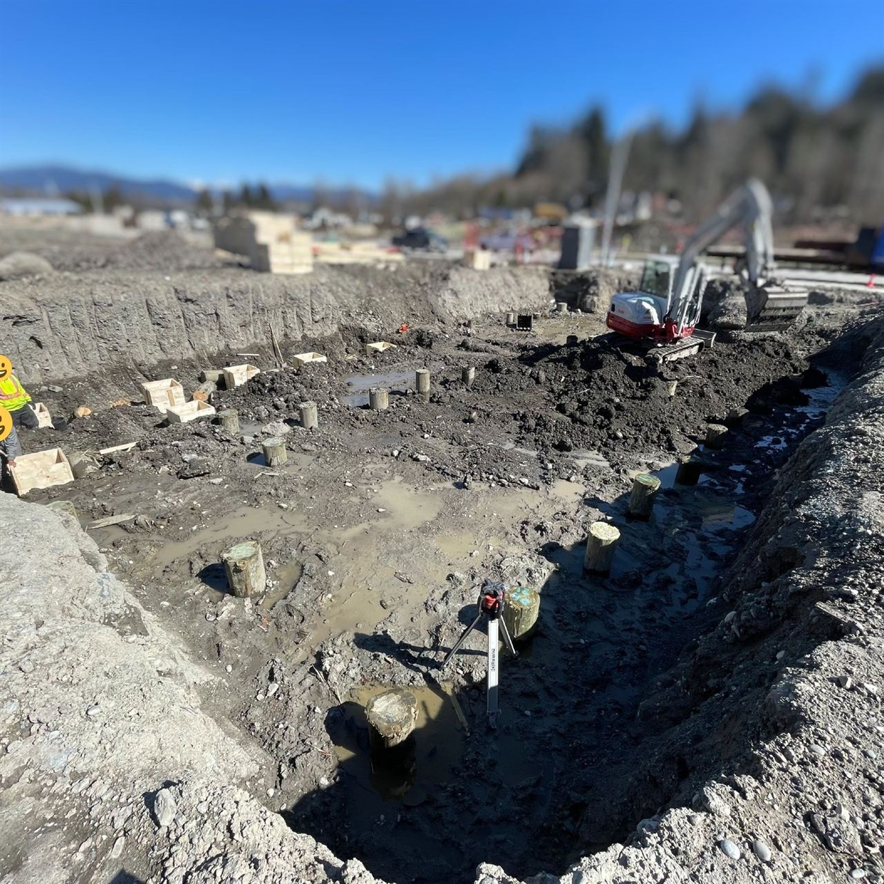 Large mass excavation site with shoring and an excavator