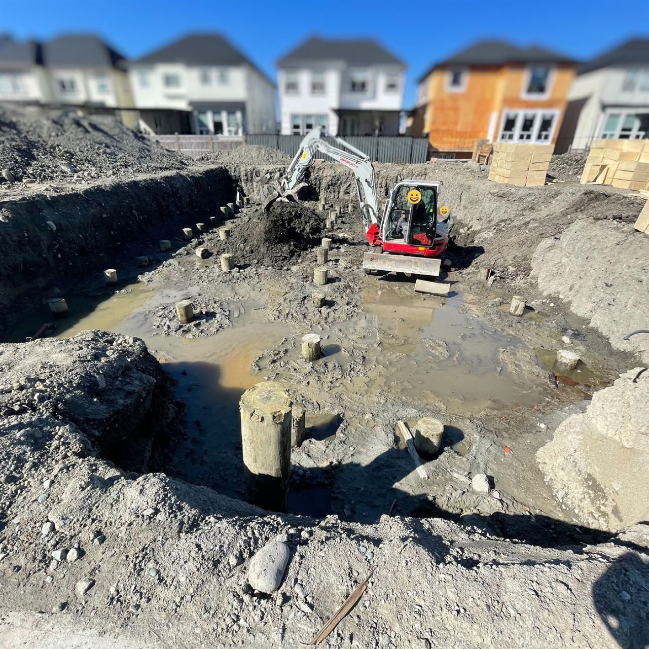 Excavator in a foundation pit with concrete piers