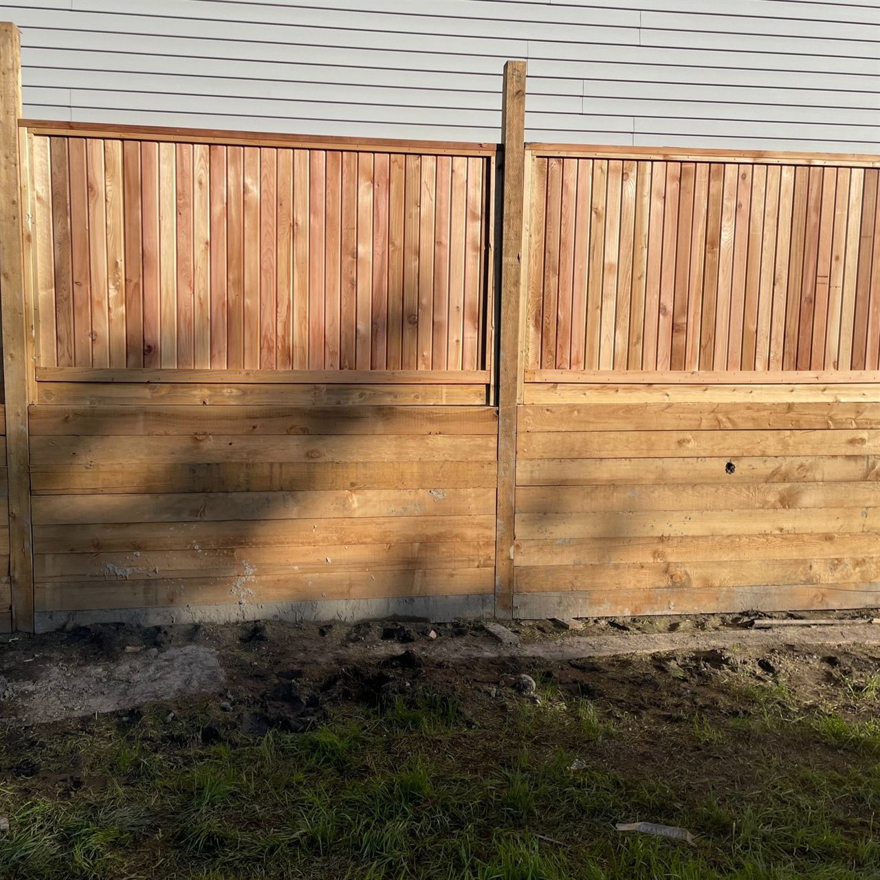 Completed cedar privacy fence panel against a house