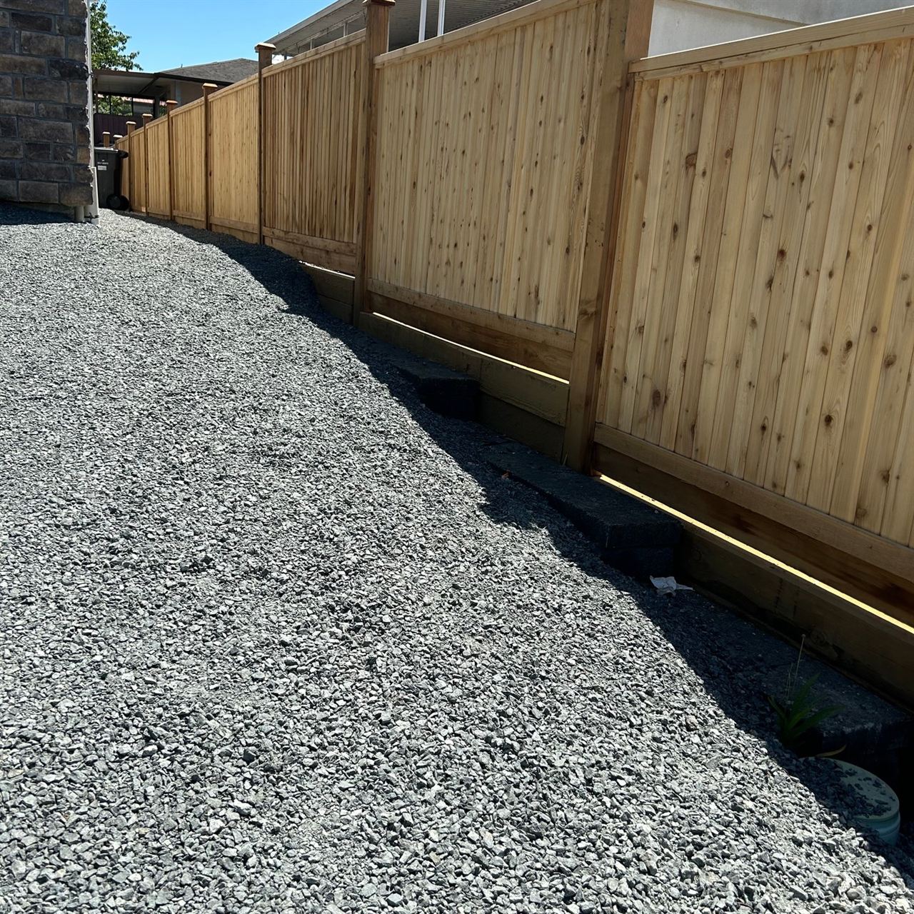 Cedar fence beside a gravel yard