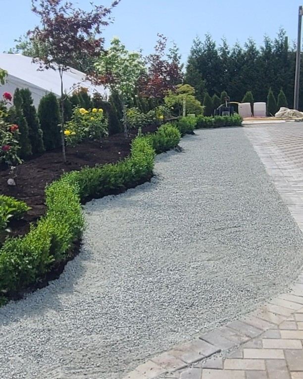 Finished garden beds, shrubs and a gravel pathway under clear sky